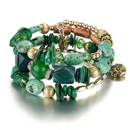 Green boho charm bracelet with mixed stone beads, gold-tone rings, and metal chain links.