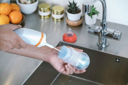 Single head attachment with white handle and blue bristle brush under kitchen faucet