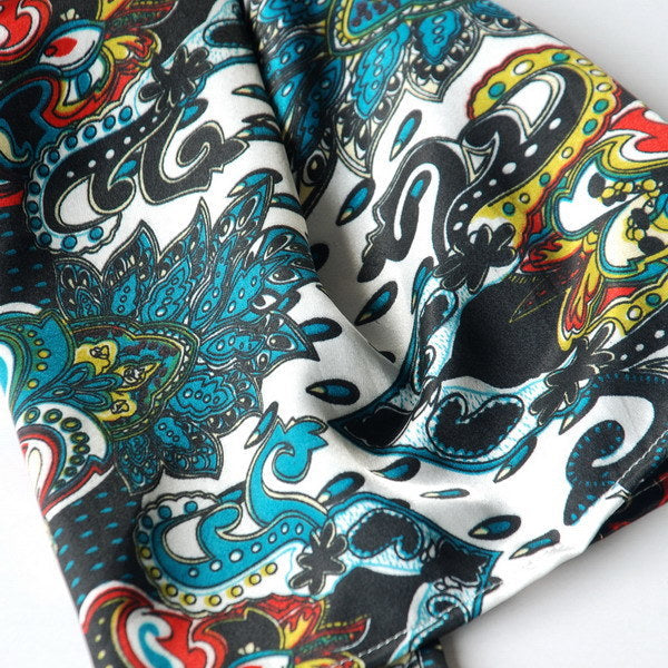 Close-up of paisley scarf fabric with teal, blue, white, and red swirling patterns