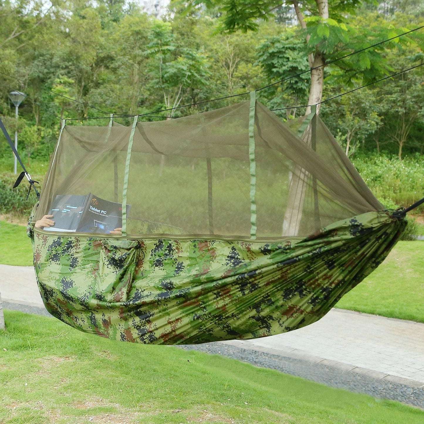 Two-person camo hammock with built-in mosquito net, outdoors on grass