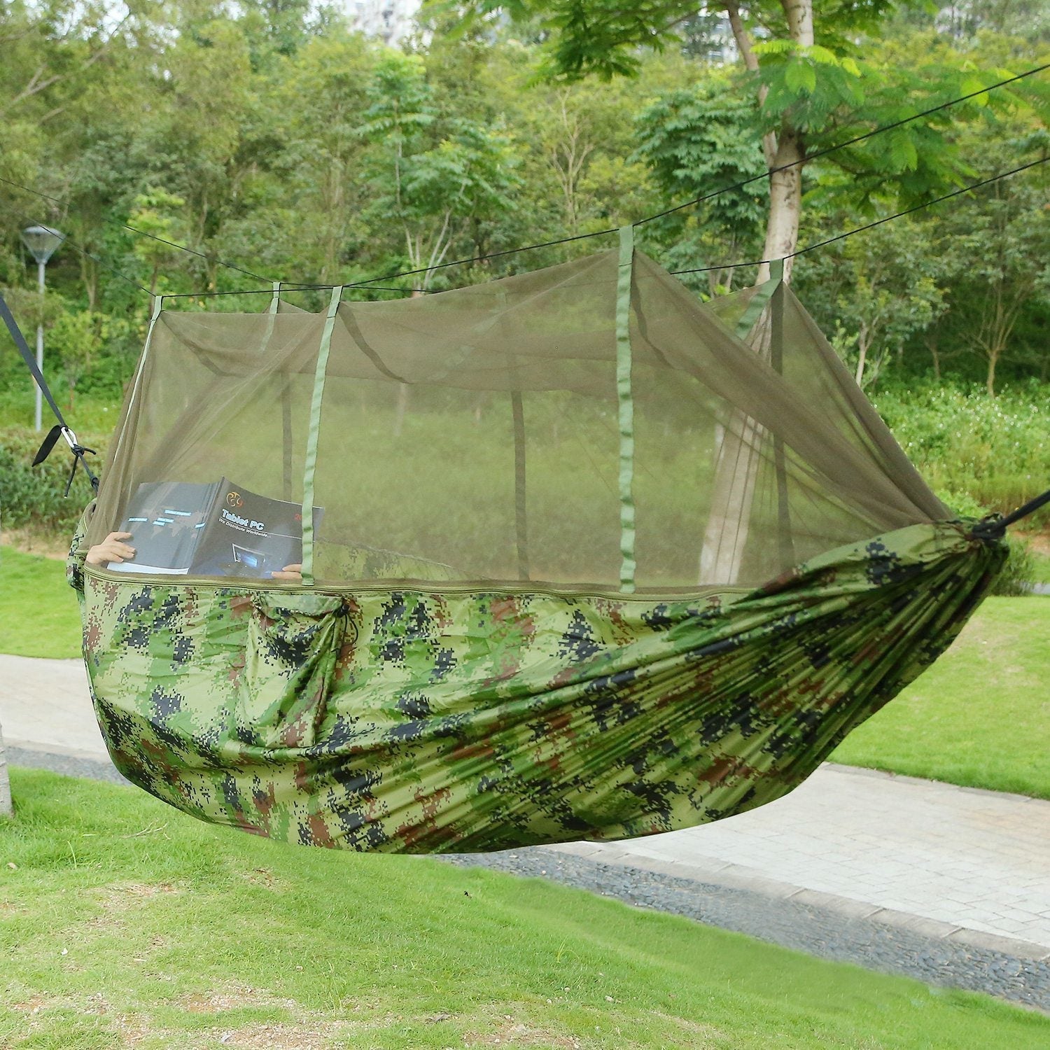 Two-person camo hammock with built-in mosquito net, outdoors on grass