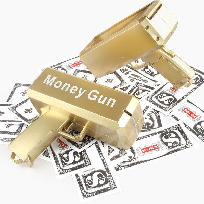 Gold toy money gun with tray open over printed prop cash bills on display