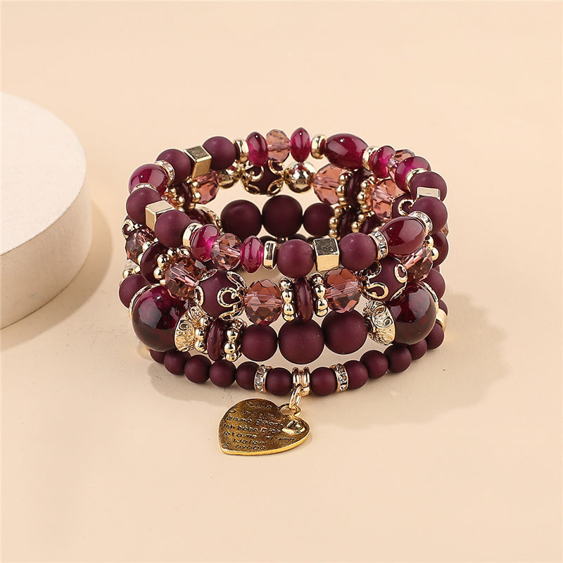 Layered bracelet set with maroon beads, gold-tone charms, faceted accents and heart drop