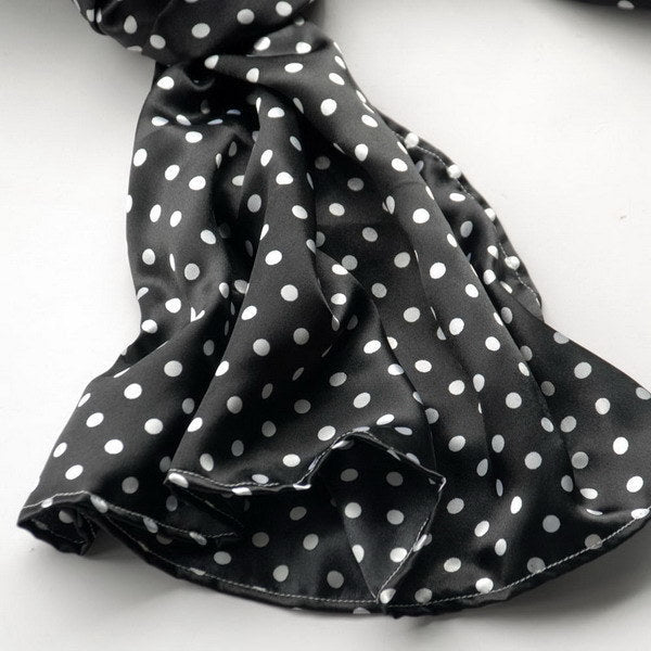Black silk scarf close-up with white polka dots, gathered and folded