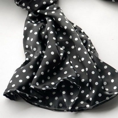 Black silk scarf close-up with white polka dots, gathered and folded
