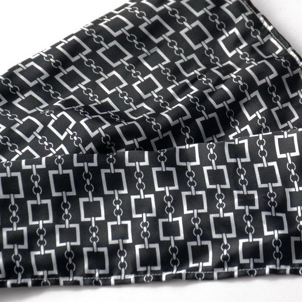 Silky black fabric close-up with white square chain motif