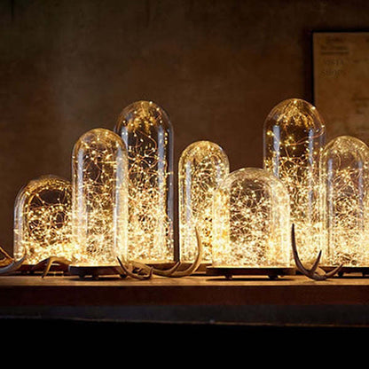 Solar string lights with multiple small clear bulb domes glowing on a dark ledge.