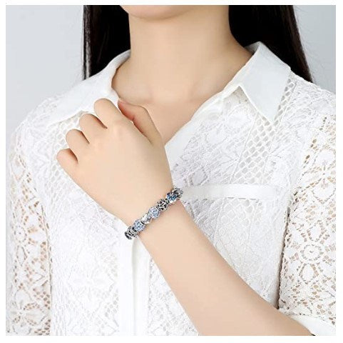 Silver-tone charm bracelet with blue sparkle beads and heart Love charm on wrist.