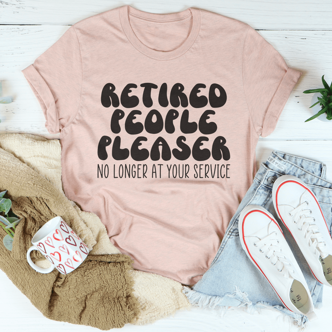 Blush pink crewneck t-shirt with "Retired People Pleaser" and "No longer at your service" text