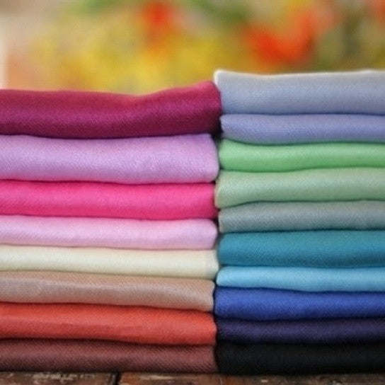 Stack of pashmina shawls in assorted colors, smooth woven fabric