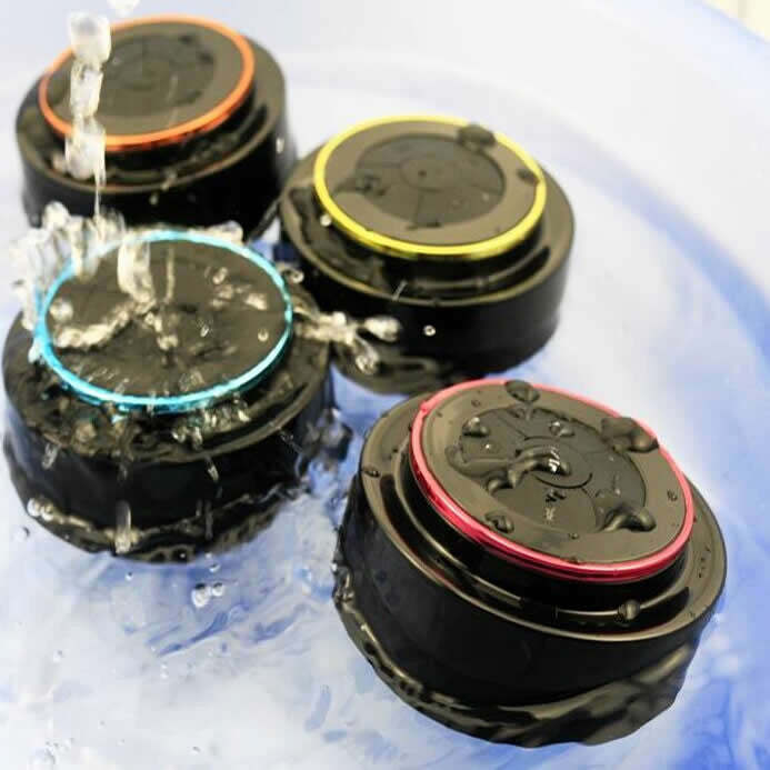 Group of waterproof Bluetooth speakers showing black bodies with colored LED rings