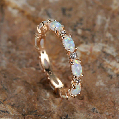Gold-tone opal-style oval ring with bezel-set center stone and small round clear accents