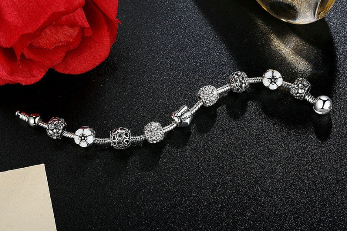 Silver-tone charm bracelet laid flat with crystal beads and small flower charms
