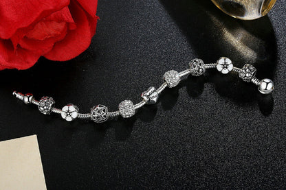 Silver-tone charm bracelet laid flat with crystal beads and small flower charms