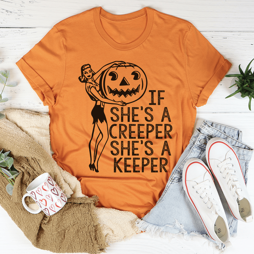 Burnt orange crewneck T-shirt with short sleeves and witch-pumpkin graphic with 'She's a keeper'.