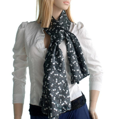 Black patterned silk scarf with white motifs, worn with a tied bow at neck