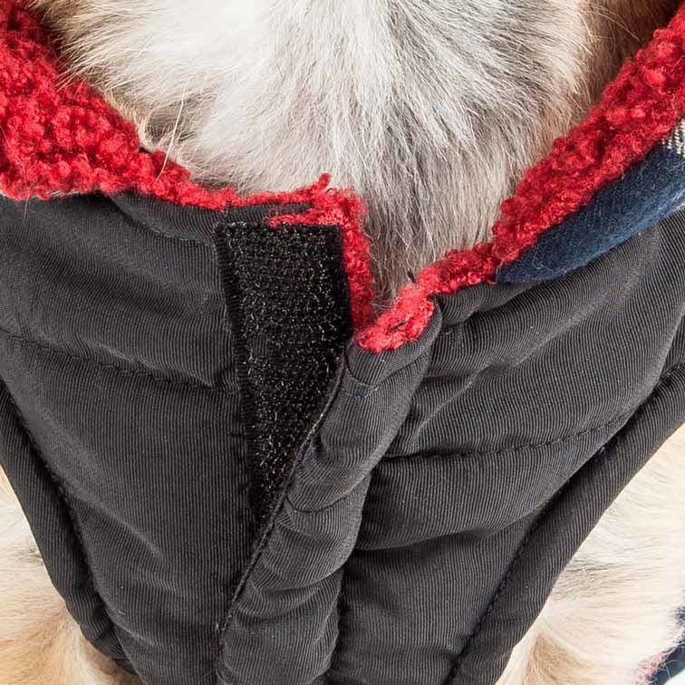 Dog jacket close-up: black insulated fabric with red fleece trim and stitched closure seam