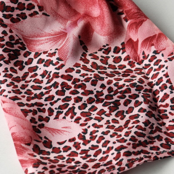 Silk scarf close-up: pink base with dark leopard spots and rose-like floral swirls