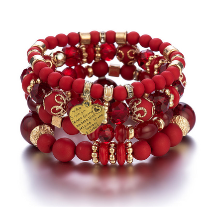 Layered beaded bracelet set with red beads, gold charms, and heart pendant