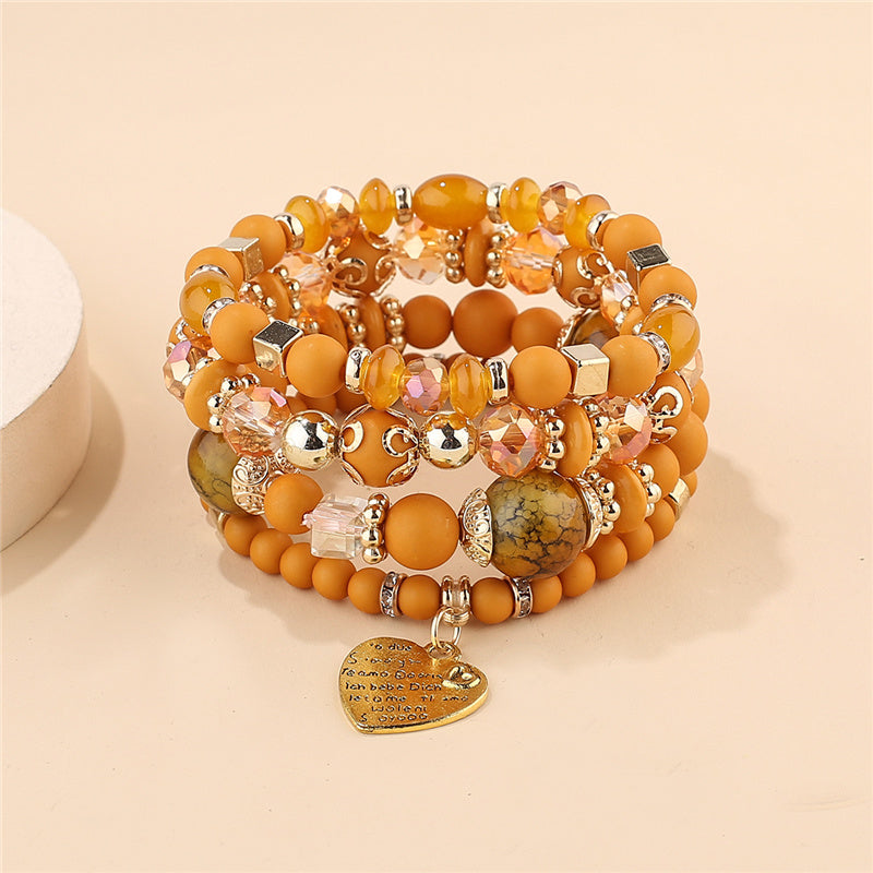 Layered charm bracelet set with orange beads, crystal charms, and a gold heart pendant