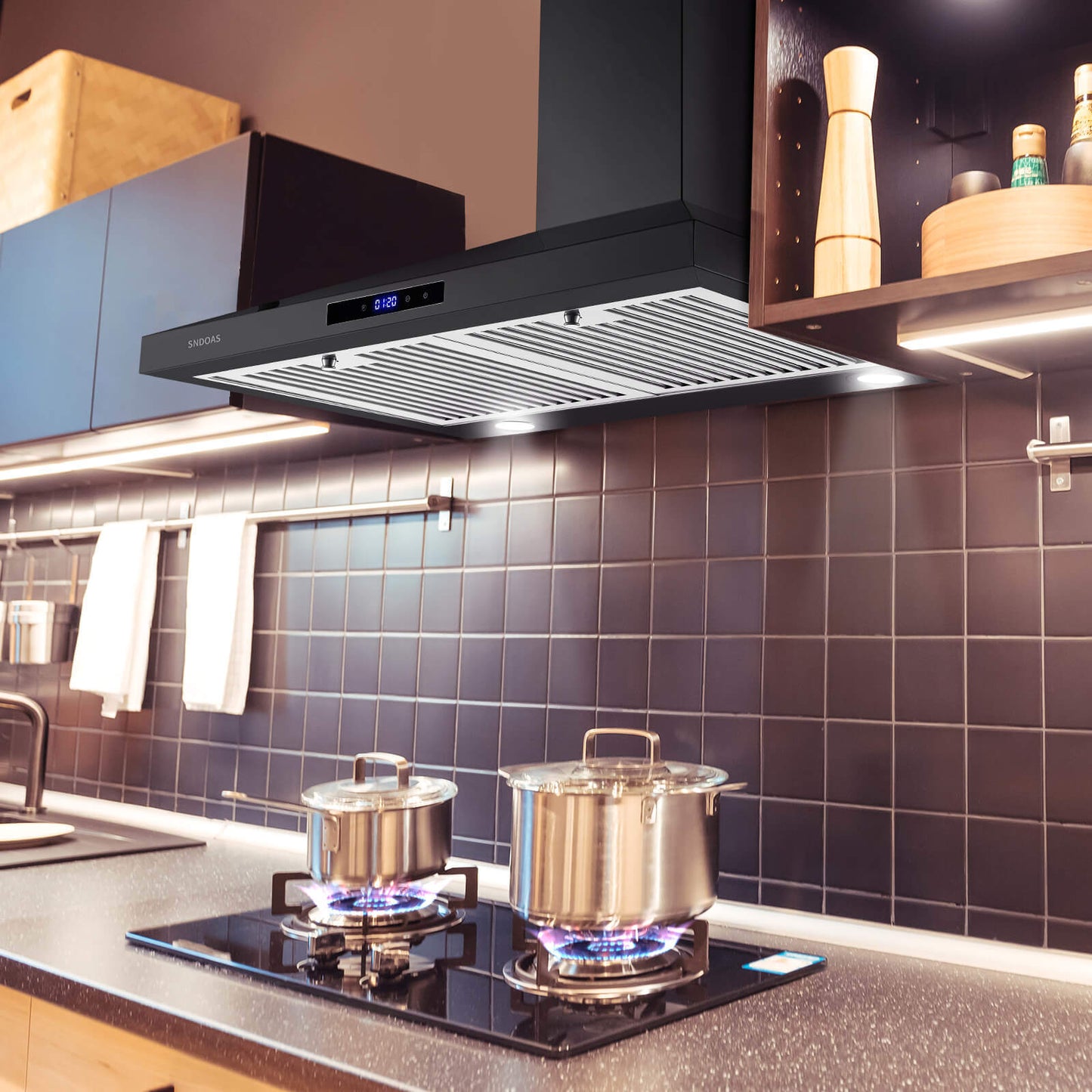 Black stainless vent hood over a cooktop with recessed underside baffle grilles
