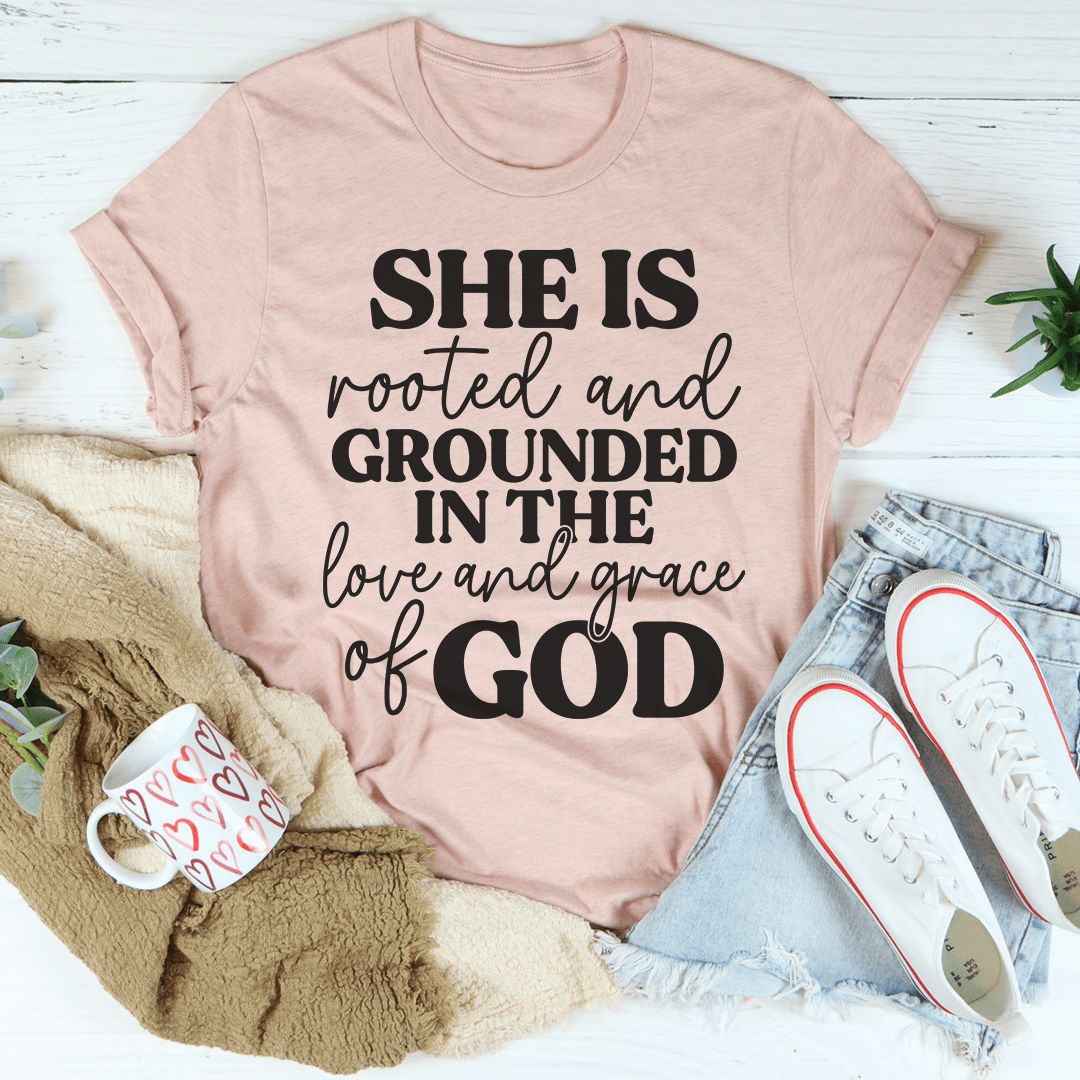 Light pink graphic T-shirt with 'SHE IS rooted and grounded in the love and grace of GOD' wording