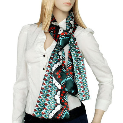 Printed scarf in dark green, red, and teal with geometric motifs worn around neck