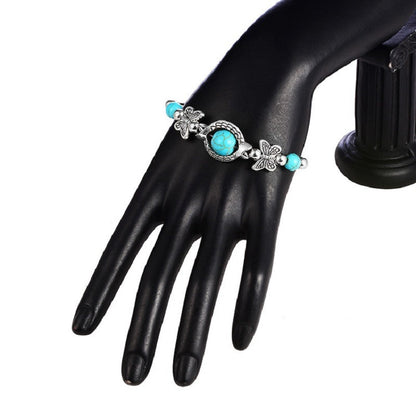 Turquoise bead butterfly bracelet worn on a black leather glove