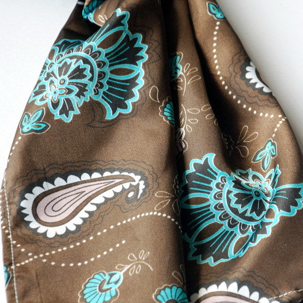 Silk scarf close-up in dark brown with turquoise and white paisley floral motifs