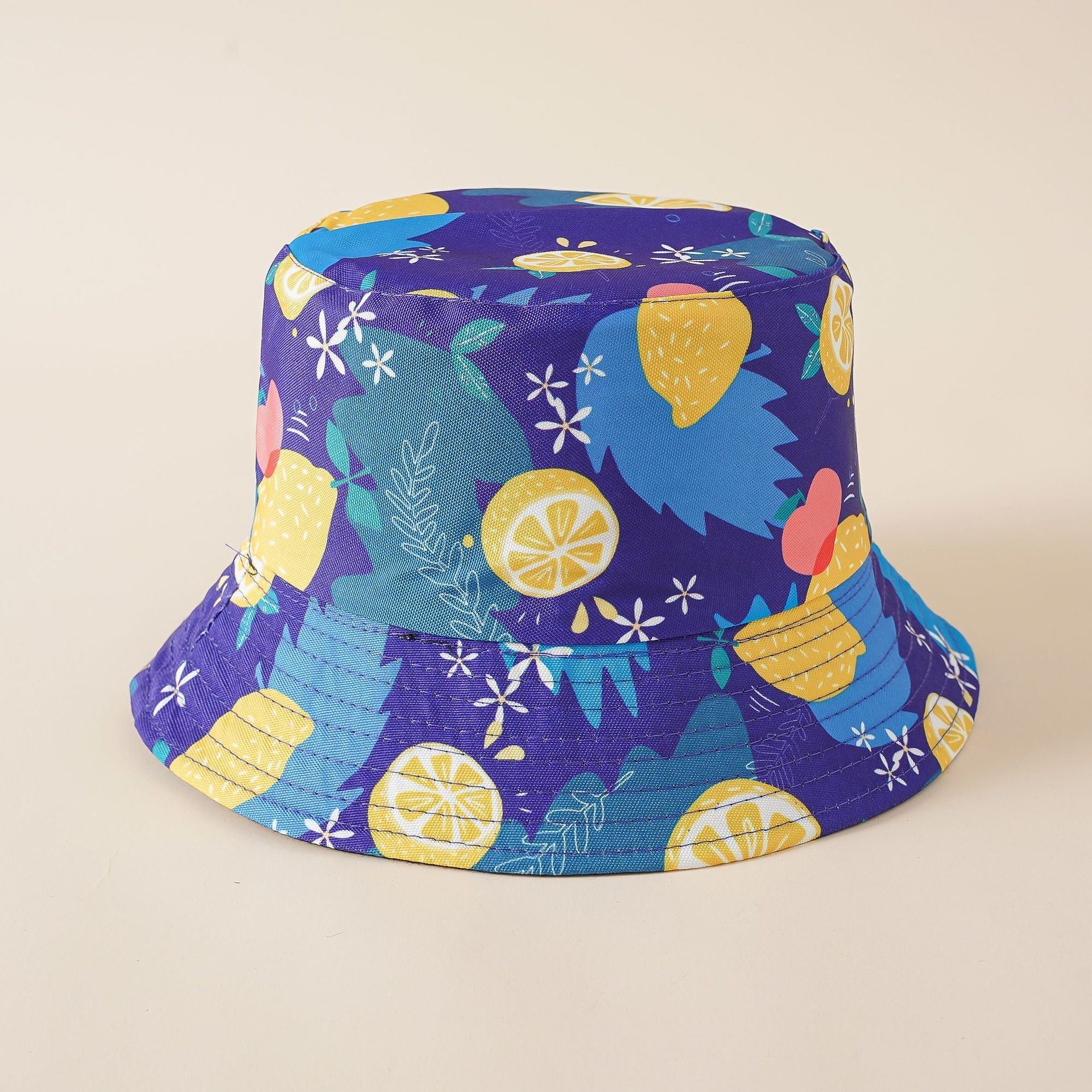 Double-sided fisherman bucket hat in purple with lemon, fruit, and leaf print