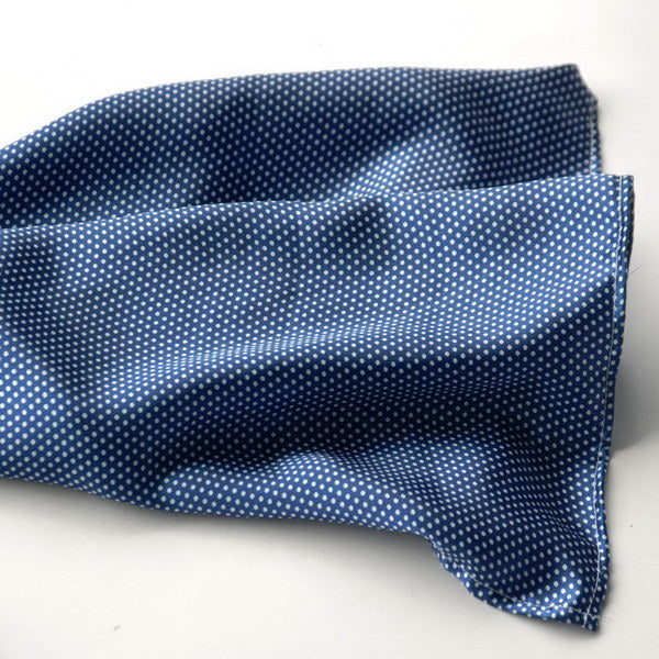 Dark blue silk scarf with white dot pattern, folded close-up