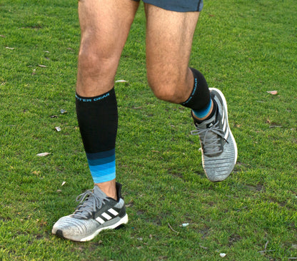 Black compression leg sleeves with light blue stripes worn on calves with running shoes