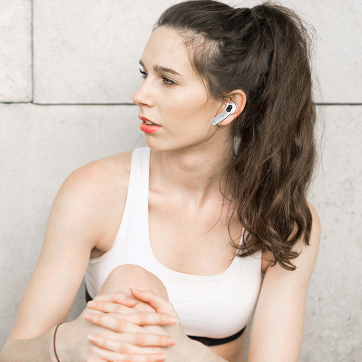 Woman wearing white Bluetooth earbuds, earbud and microphone stem visible