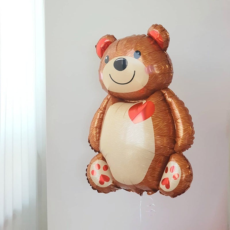 Brown bear foil balloon with red heart on white belly; strings hanging