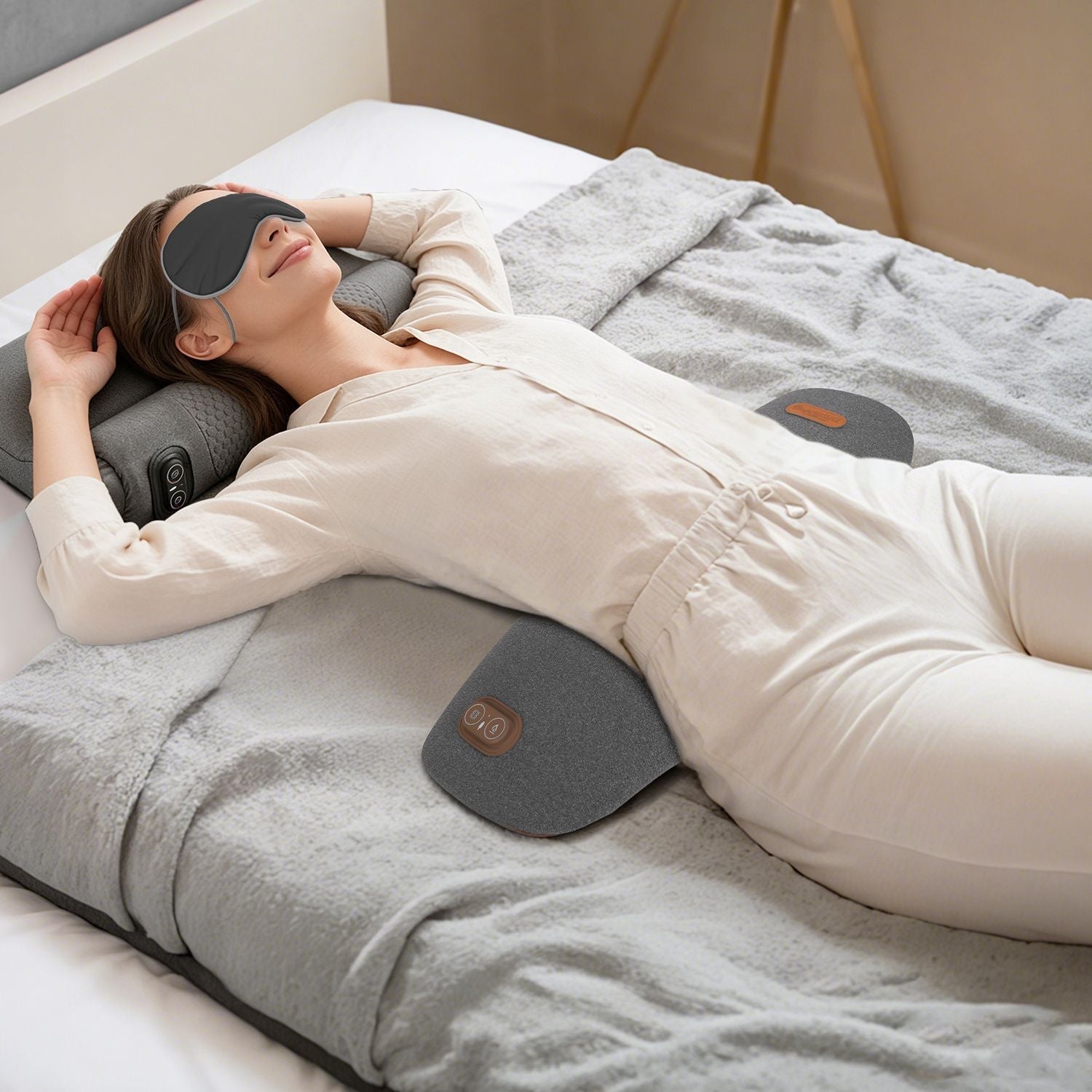 Dark grey lumbar massager pillow with controller pads, placed under lower back