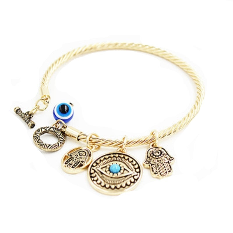 Twisted charm bracelet with evil eye and hamsa charms, blue enamel accents, gold-tone finish.