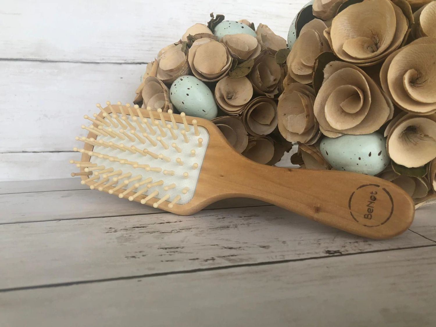 Wooden detangling hair brush with white pin bristles on light wood base