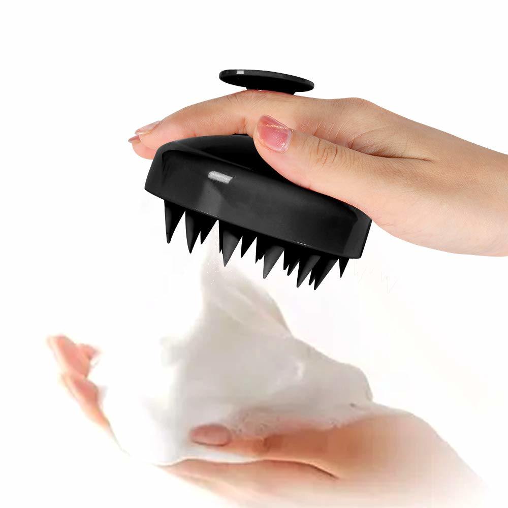 Black silicone scalp massage brush with pointed spikes, held in hand