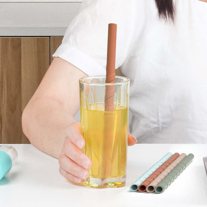 Reusable silicone straw in yellow drink with pastel straws beside the glass
