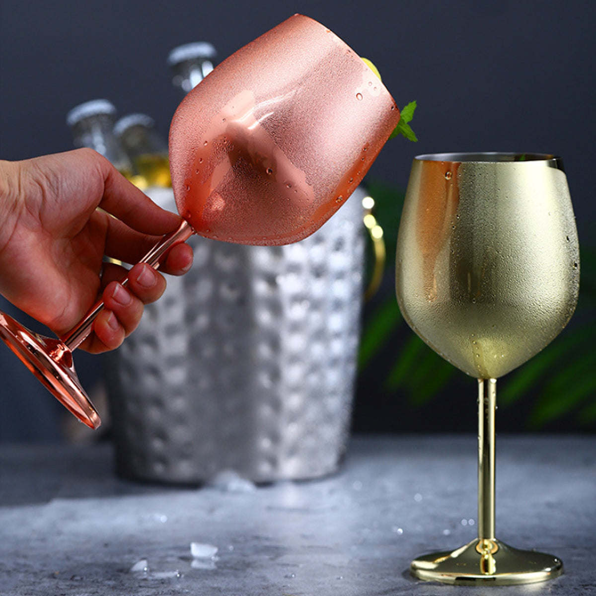 Rose metallic champagne flute held in hand with condensation, next to gold glass