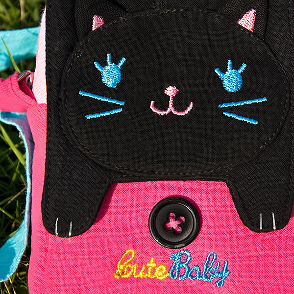 Embroidered cat face applique on black flap with pink panel and round snap button.
