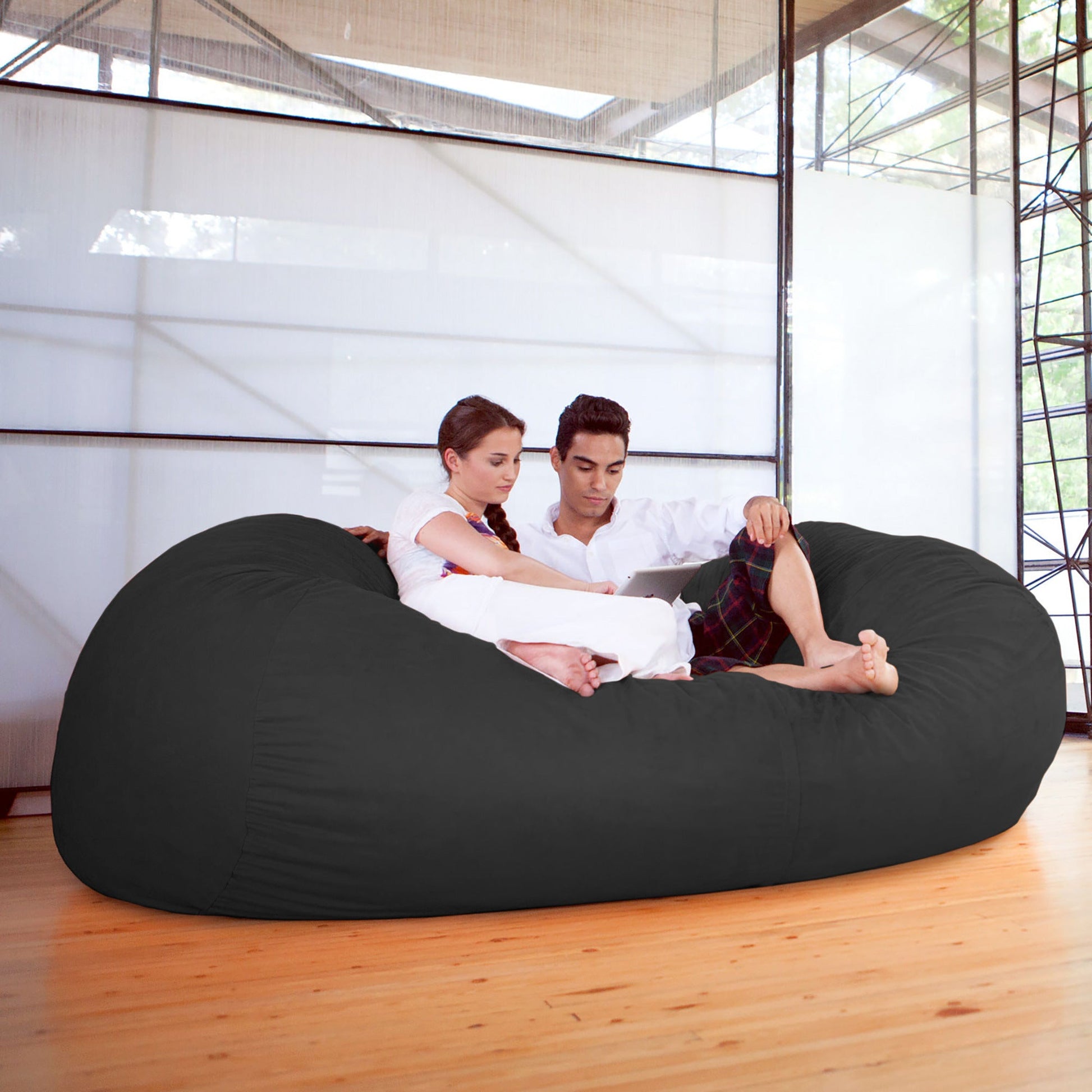 Black giant bean bag sofa, large rounded seat with two people lounging