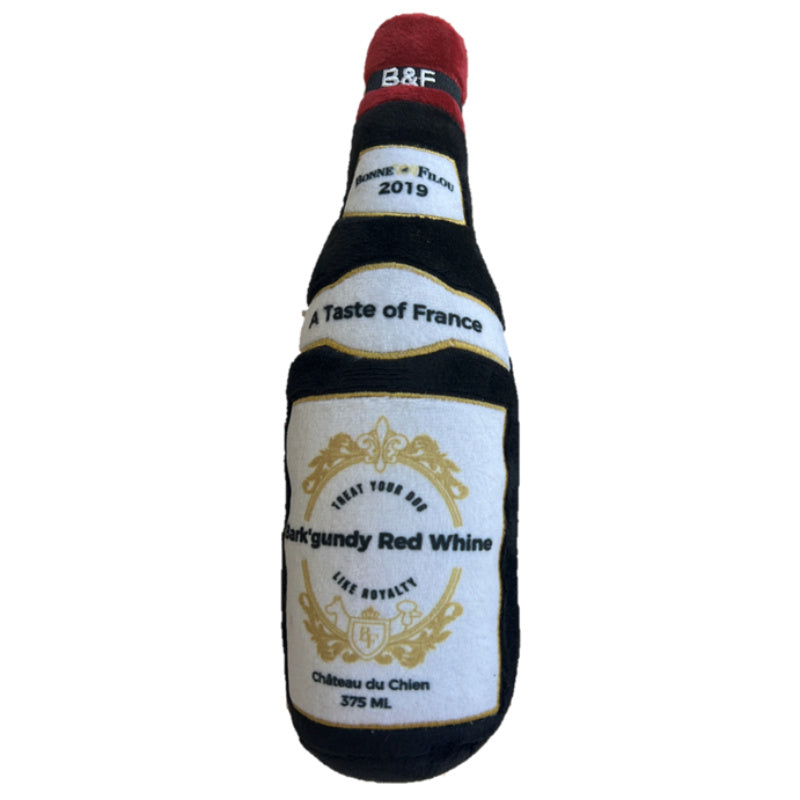 Wine bottle squeaky dog plush toy close-up with red top, black stripes, and gold crest label