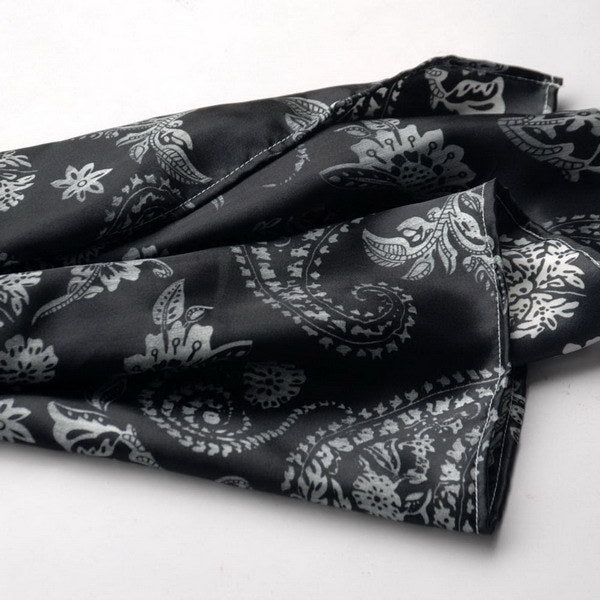 Black silk scarf close-up with white paisley and flower motifs