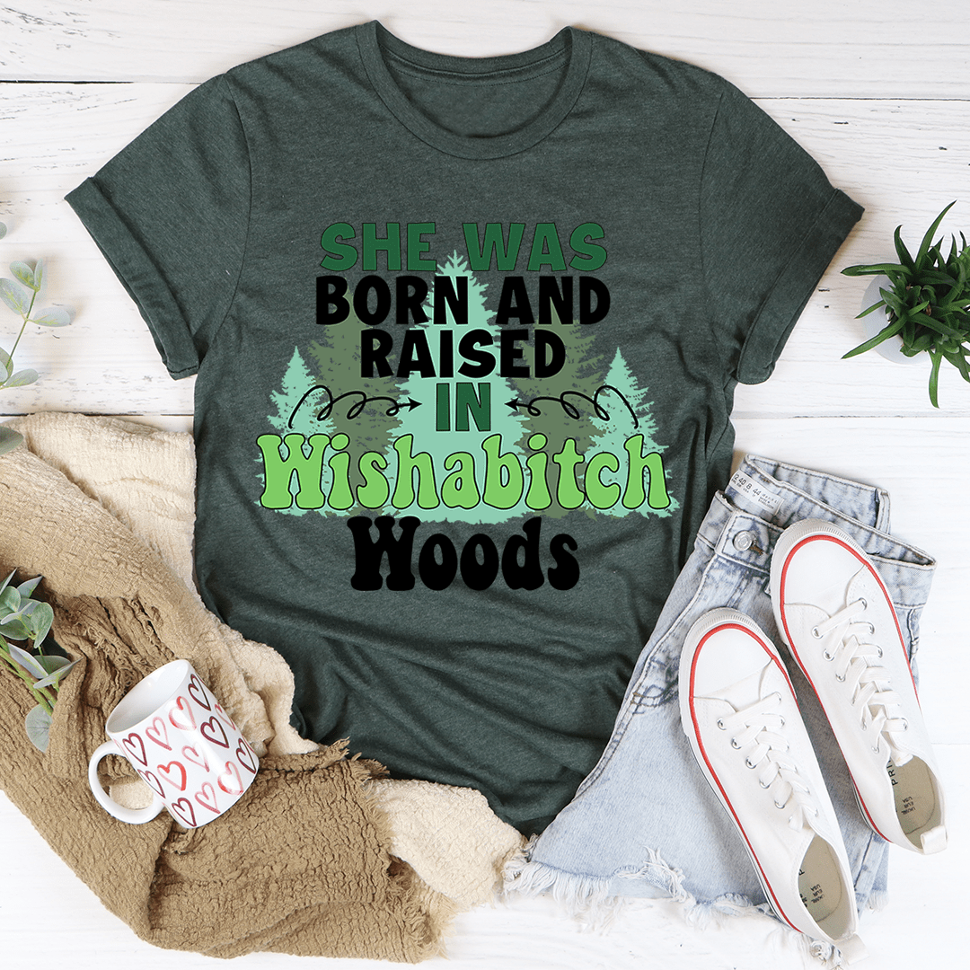 Dark green graphic T-shirt: 'She Was Born and Raised in Wishabitch Woods' tree print