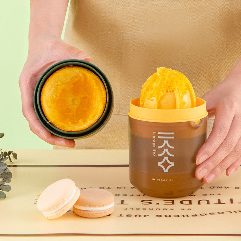 Portable manual citrus juicer in use with orange halves and opened juicing cup