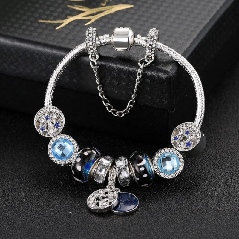 Silver-tone charm bracelet with blue crystal charms, black beads, and star disc dangles