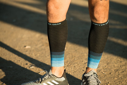 Black compression calf sleeves with light blue stripes and arched logo text on cuff
