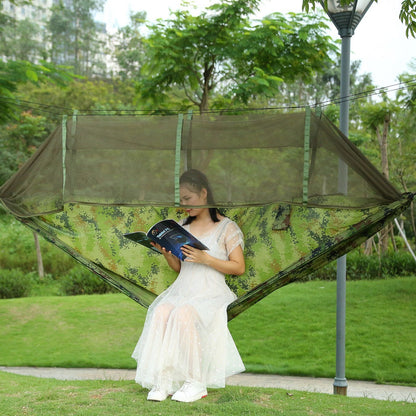 Two-person camo hammock with mosquito net, person relaxing outdoors on grass