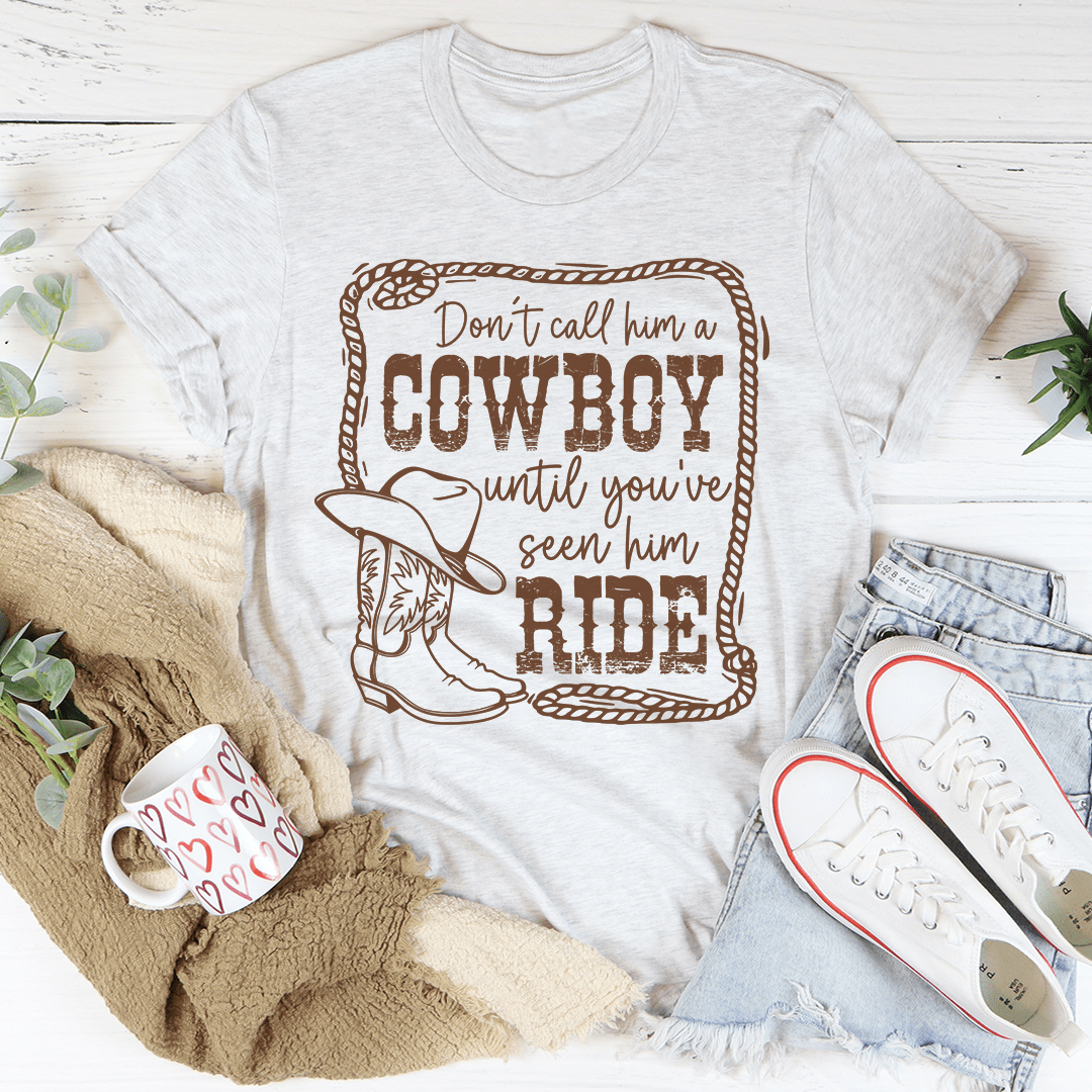 Light heather gray crewneck cowboy slogan t-shirt with western print: Don't call him a Cowboy until you've seen him ride